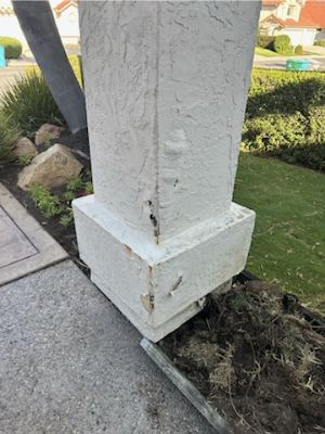 Localized damaged stucco at the base and edge of an exterior pillar