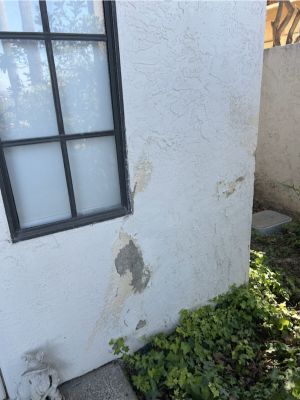 Localized missing and damaged stucco below an exterior window